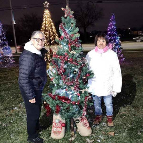 two women posing next to Christmas tree