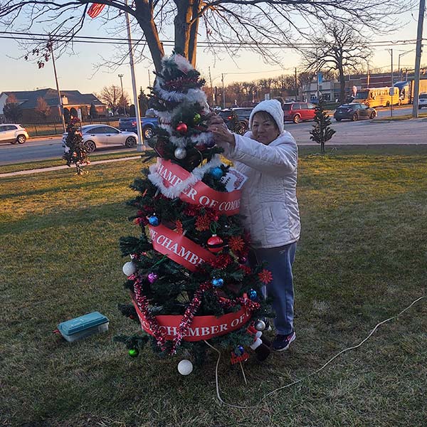 woman hanging garland on a Christmas tree